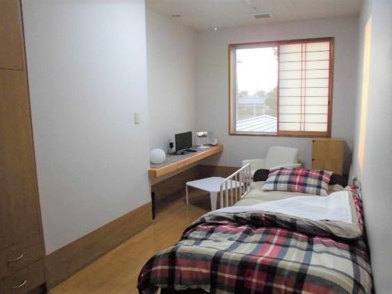 障子が窓に付けられた和風の居室。ベッドやテーブルセットがあり、収納も大きい。