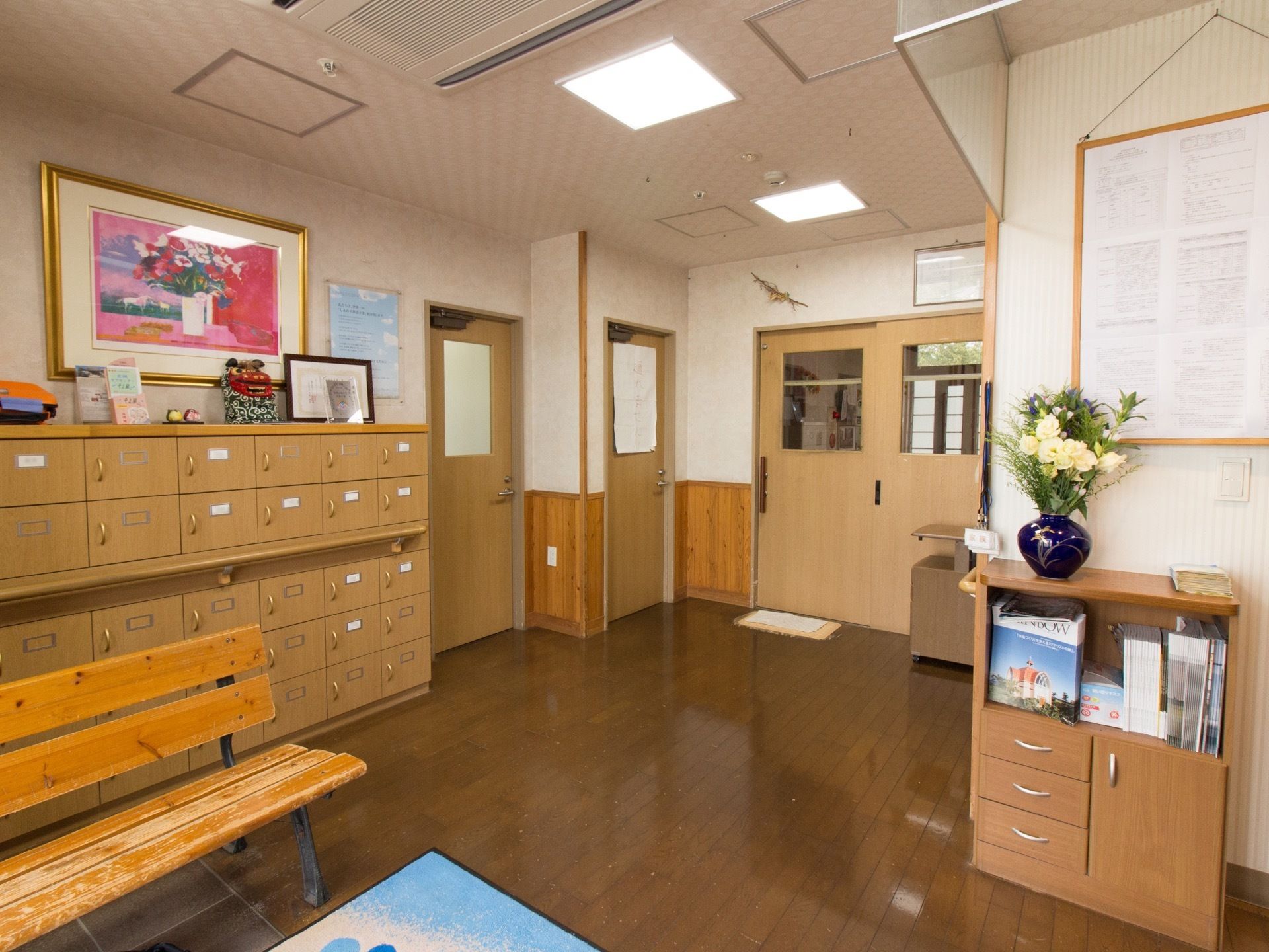 玄関に設置された靴箱は入居者様各々に仕切られており、扉には名前が書かれている。壁には花の絵が飾られている。