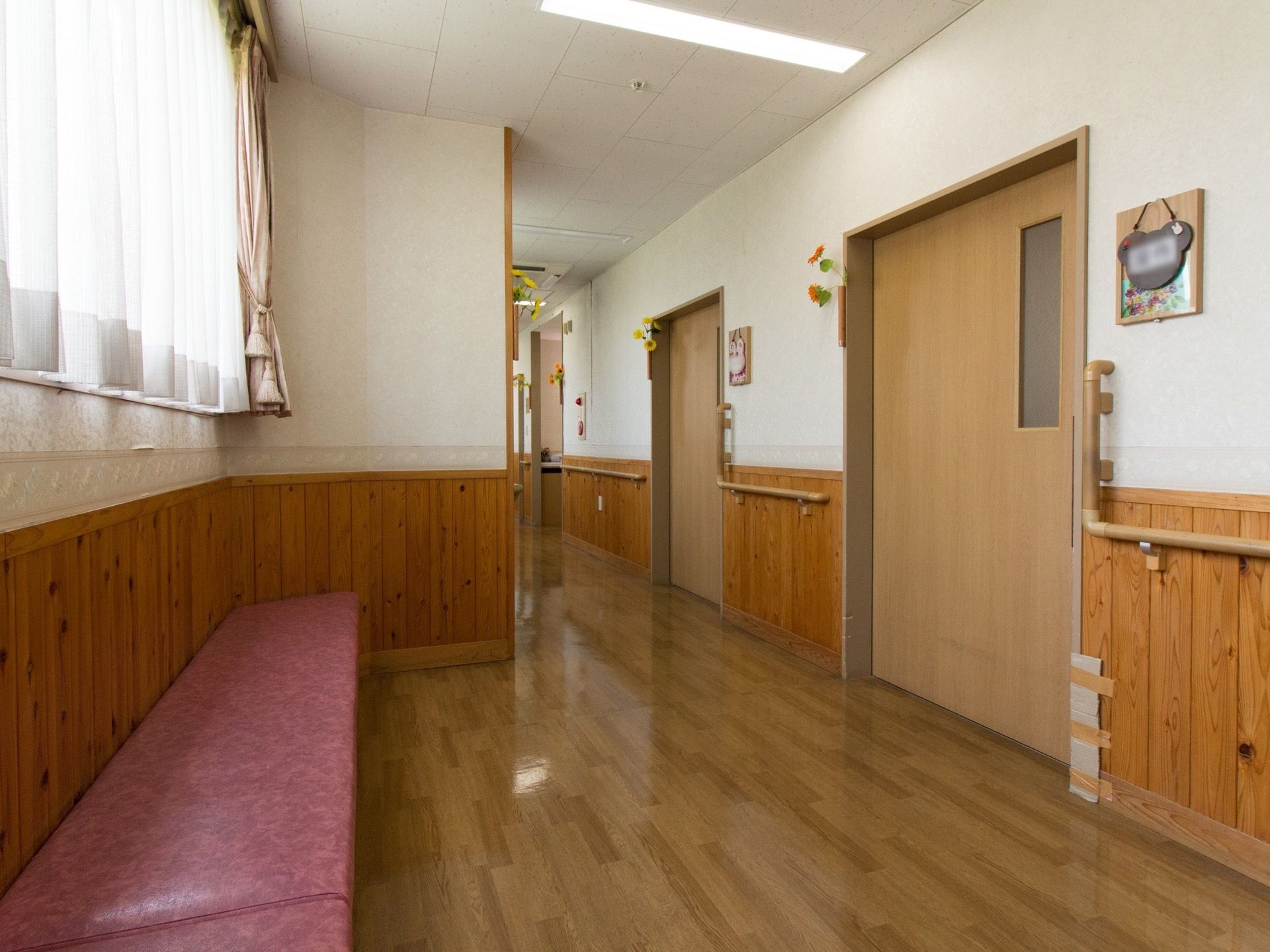 居室が立ち並ぶ廊下で床はフローリングとなっている。ドアの横の壁には、動物をモチーフにした表札が掛けられている。