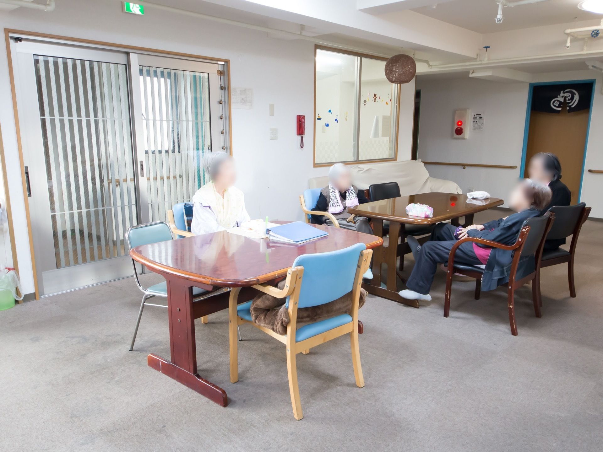 広々とした食堂である。４人掛けテーブルやソファが配置されており、火災報知器や非常通報用の電話機、手すりが設置されている。