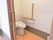 左にスライドする扉を開けるとトイレになっている。トイレットペーパーフォルダーが２つ付いており手すりと一体になっている。