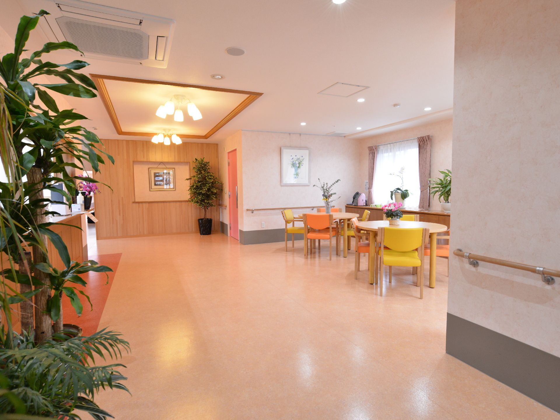 ゆったりとしたエントランスには２つの照明が輝いている。壁にはアートが飾られ、観葉植物なども配置されている。