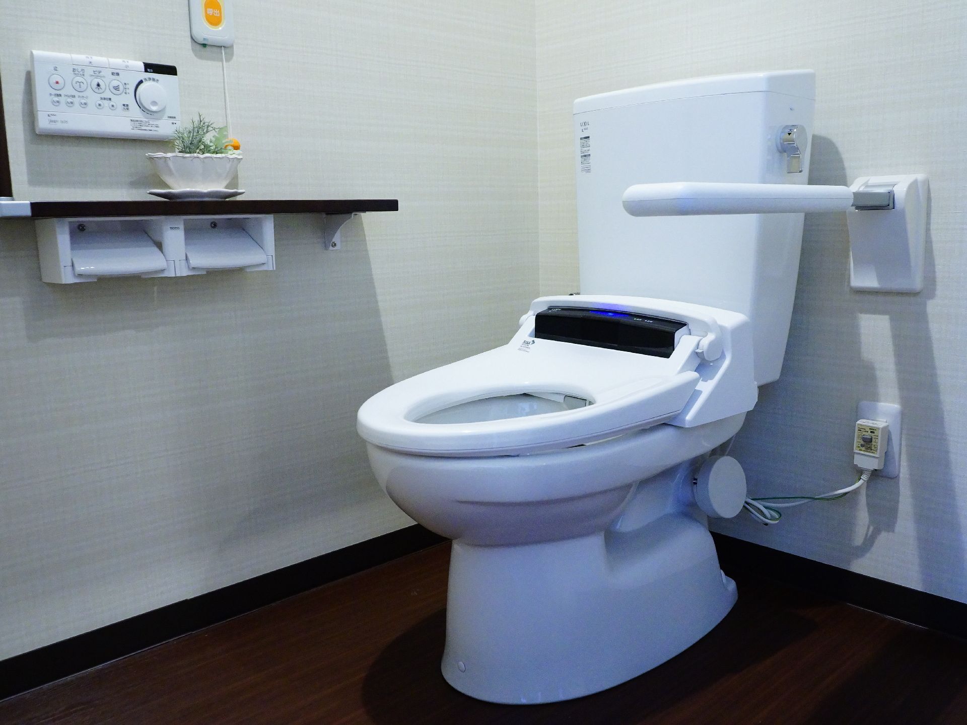 ウオッシュレット式のトイレは手すりもついている。各種機能がついているリモコンは壁際に呼び出しベルとともにあり、そちらにも手すりがある。