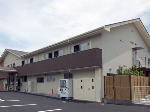 ２階建ての横に長い建物で、駐車場に面している。２階には窓が並んでおり、１階には自動販売機が設置されている。