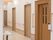 エレベーター、スタッフルーム、トイレが並ぶ通路。壁伝いに手すりが設置されている。各部屋のドアは木目調で統一されている。