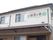 施設建物の２階の壁に大きく施設名称が入っている。横には居室の窓がある。１階のひさしの上にエアコンの室外機が設置されている。
