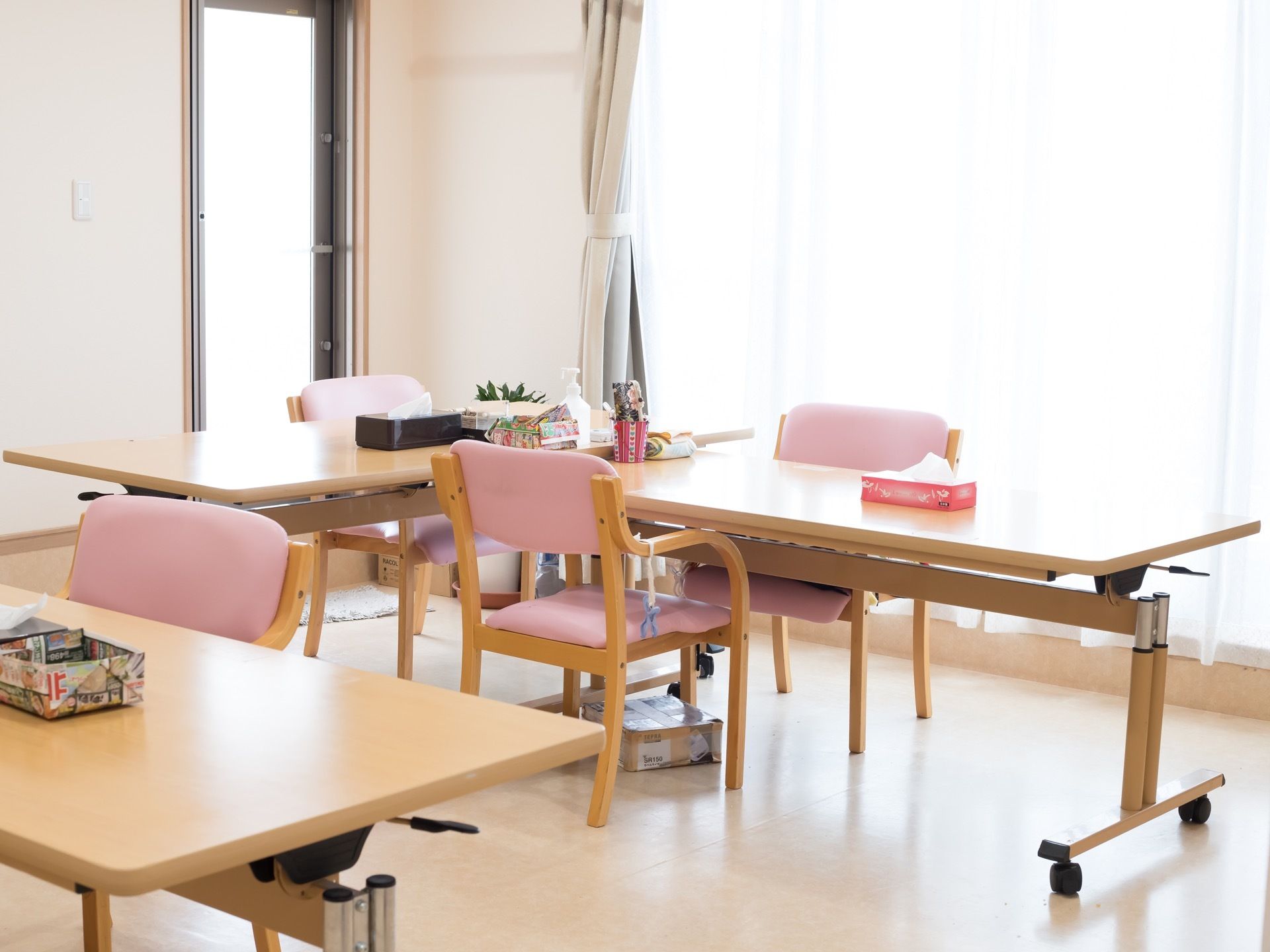 折りたたみ式のテーブルと木製の椅子がセットされ、数組配置してある。部屋には陽光が差し込み、明るくなっている。