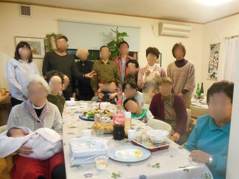 テーブルの上にご馳走が並び、その周囲に大人に加えて子供や赤ちゃんが集まっている様子