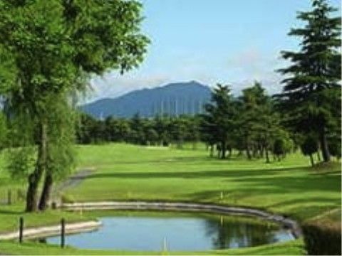 自然の中にあるきれいに整備された芝生が広がるゴルフ場。ところどころに木が生えている。遠くには山が見える。