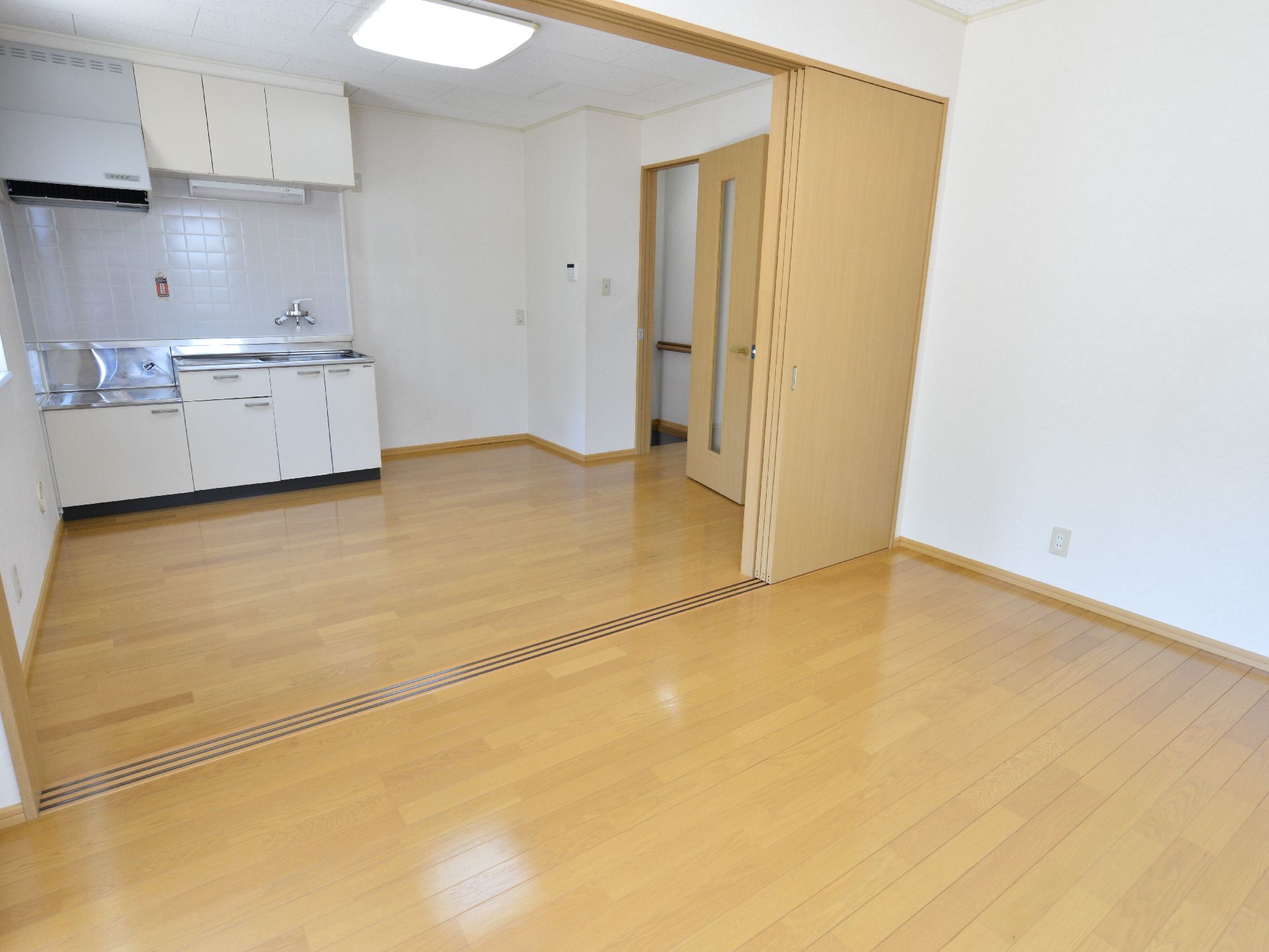 4枚のスライド式の戸が部屋を仕切っている。左奥のキッチンには換気扇もついており上部と下部に収納も用意されている。