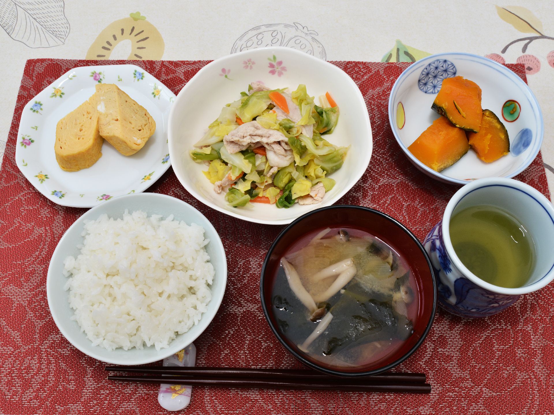 ごはんに味噌汁、卵焼き、野菜炒め、ふかしたかぼちゃ、お茶。純和風のメニューがランチョンマットの上に箸とともに並んでいる。
