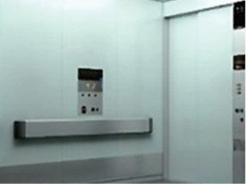 奥行、幅ともに十分な広さをとっているエレベーター。内部は落ち着いたグレー系になっている。入り口と壁に乗り降りボタンが設置されている。