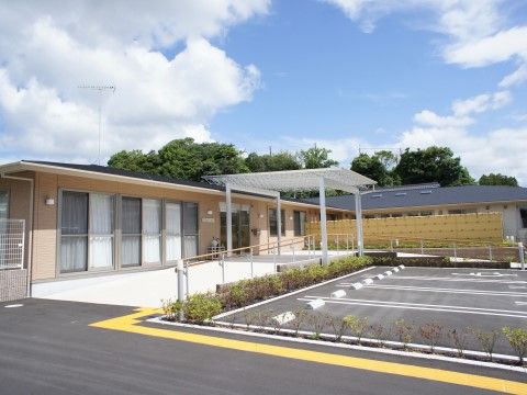 建物の前に駐車スペースが広がっている、平屋造りの施設外観