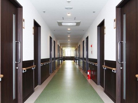 両側に居室のドアや手すりが並び、まっすぐに伸びているフローリングの廊下