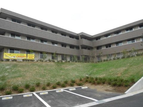 ３階建てのモダンな施設には、広々とした駐車場が完備されている。周りには緑が茂り落ち着いた中で生活することができる。