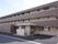 施設の外観である。三階建ての建物で、出入り口近くに看板が設置されている。敷地は広いスペースを確保している。