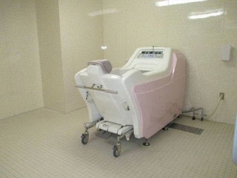 クリーム色の浴室に設置されている、ピンク色の入浴補助機器