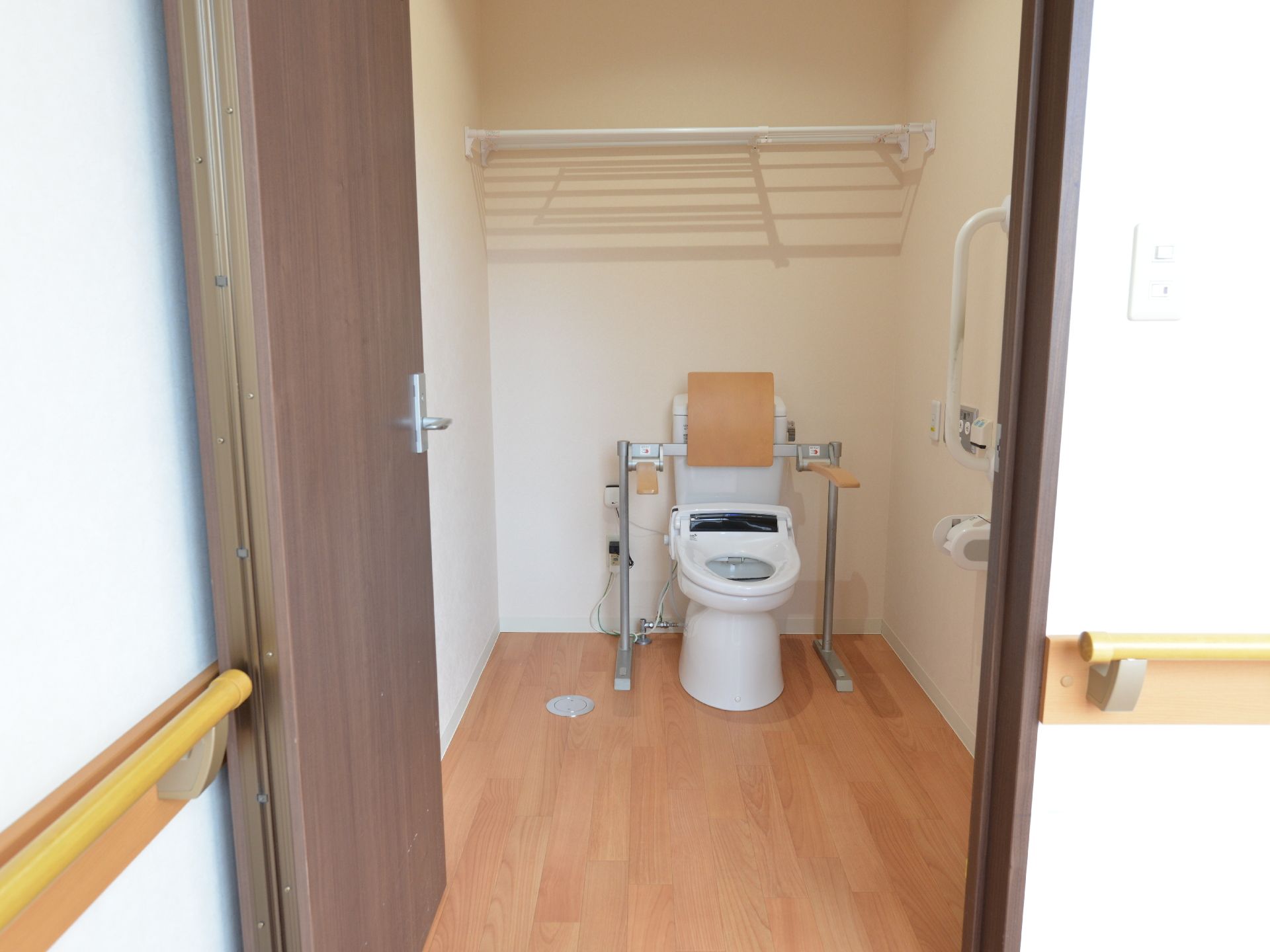 扉手前にはしっかりと手すりが備え付けられており、トイレの周りにも補助機材が設置してある。頭上に物を置けるようになっている。