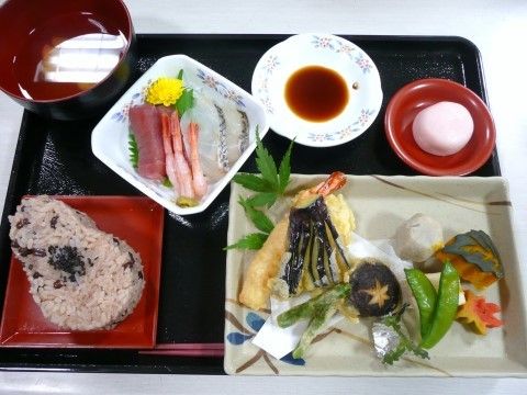 赤飯が主食で、天ぷらや刺身などが盛り付けられている豪華な食事