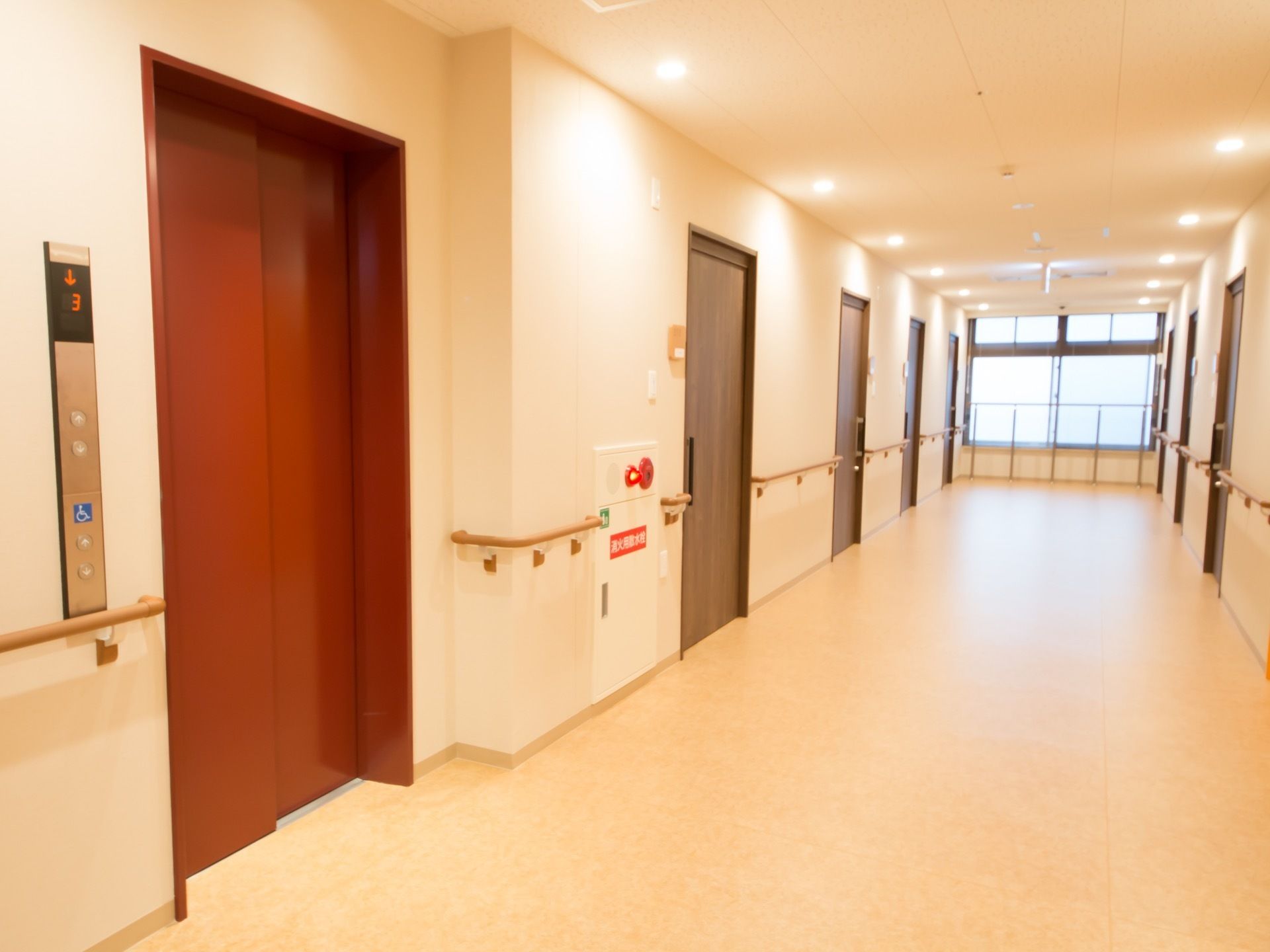 施設内の廊下は横幅を広く設けたつくりになっている。エレベーターがあり、その横には消火栓が設置されている。