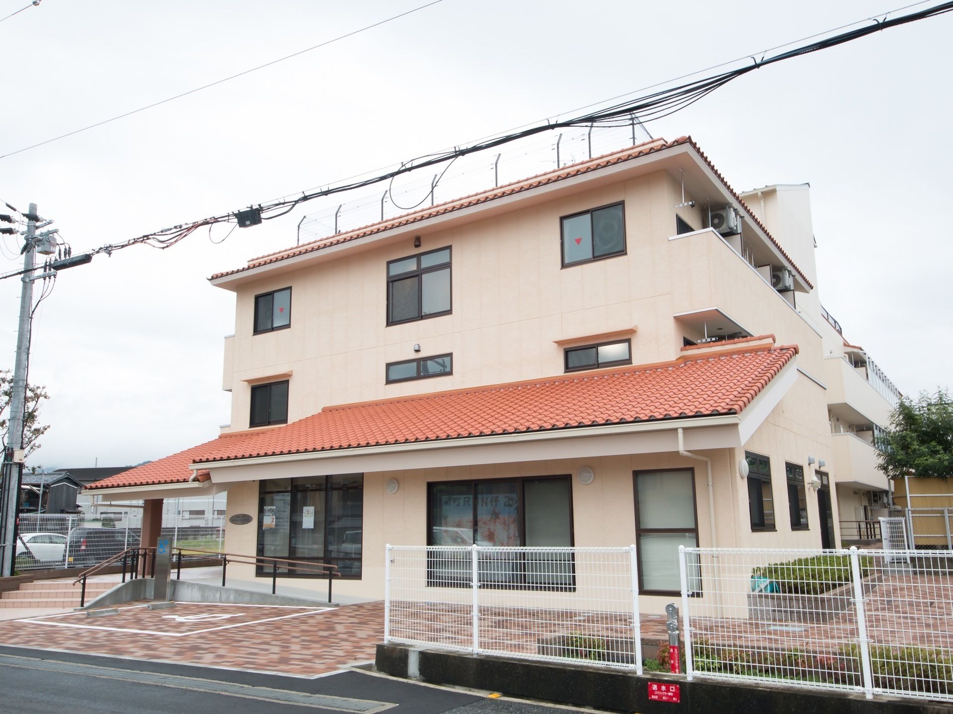建物は３階建ての構造をしている。各居室のベランダにはひさしがあり、エアコン用室外機が取りつけられている。