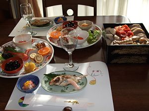 重箱に入った野菜の煮物や焼き魚や卵焼き、黒豆やフルーツのセット
