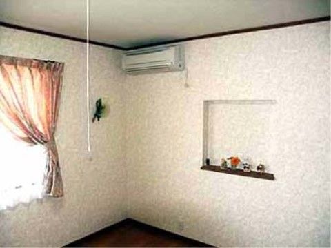 壁にはおしゃれな掘り込み棚があり、その上には置物が飾られている。棚の上部にはエアコンが設置されている。