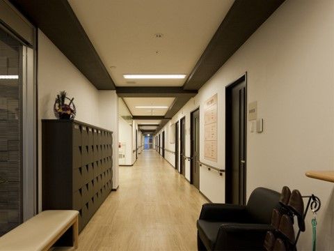 こげ茶色の下駄箱の横に、白いベンチ椅子が置かれている施設玄関