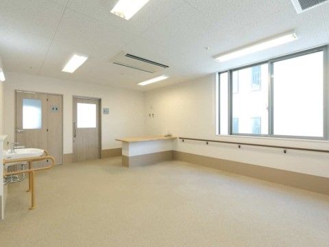 白い壁に淡いベージュの床の室内となっている。天井には空調が設置されている。入口付近にはカウンターテーブルがある。