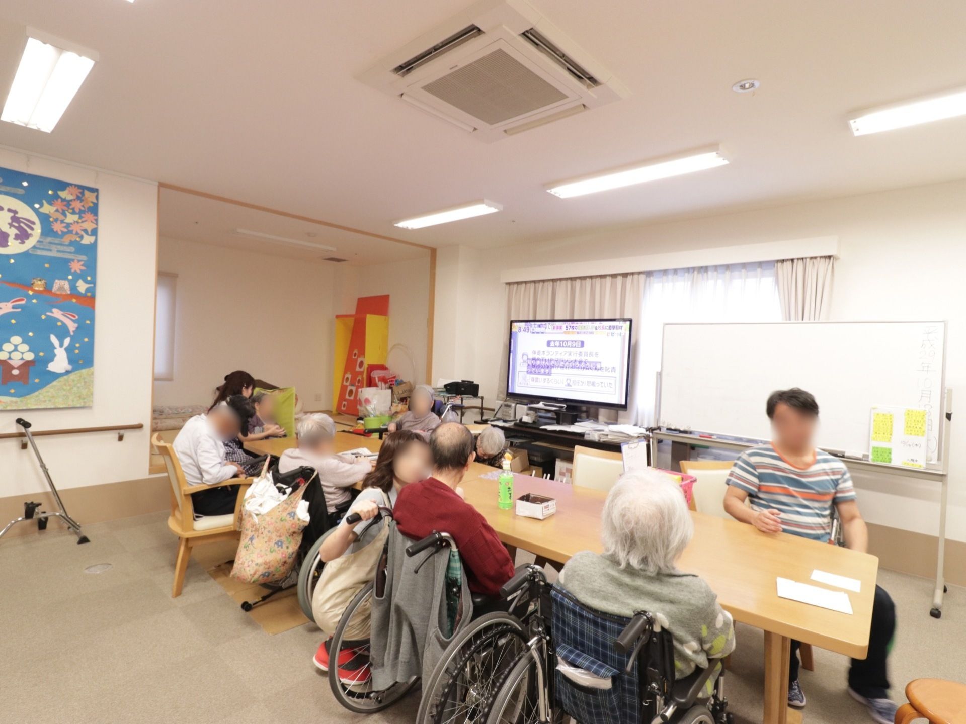 食堂の奥には、薄型テレビが置かれている。その隣には、ホワイトボードがある。壁には、月見をしているウサギが描かれた絵が掛かっている。