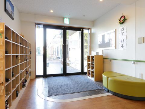 ガラスの観音開き式のドアが設置され、玄関マットが敷かれている施設の入口