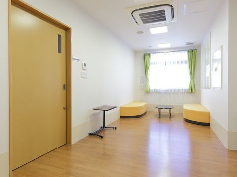 窓の近くにオレンジ色のソファーが左右に設置され、真ん中に丸テーブルが置かれている共有スペース