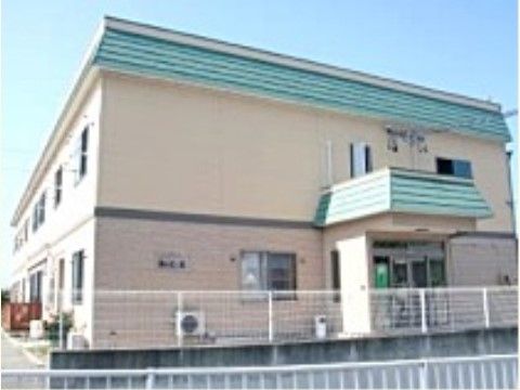 玄関前に雨除けルーフが設置された、白い柵に囲まれている施設外観