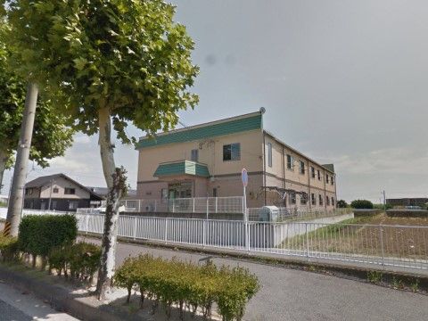 施設から一段高い道路から、建物正面を望む。緑色のひさしが付いた玄関は、扉がガラス製で、自動式になっている。