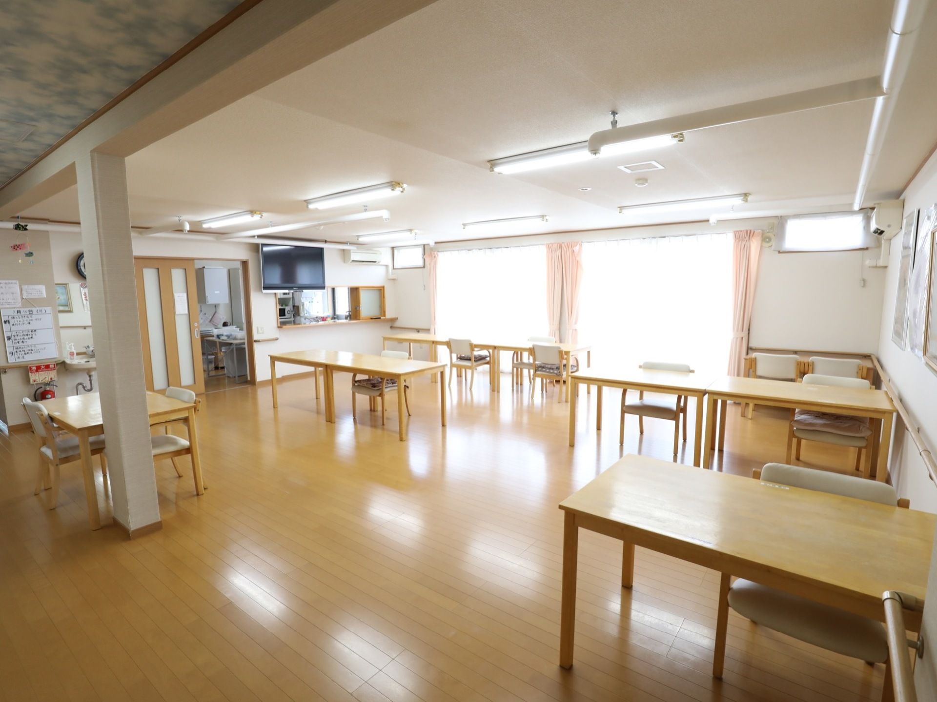 幅の広い窓を設置したフロアで、自然光がたっぷり降りそそぐ。テーブルと椅子が、隣同士ゆとりをもって配置されている。