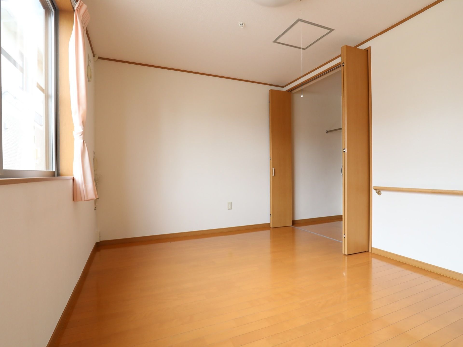 木目調の床に施された、広い空間が印象的な居室である。両開き仕様のクローゼットも完備されており、ハンガーポールもある。