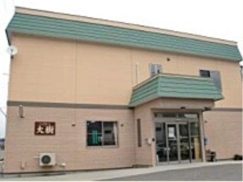 屋根の部分が緑色で、外壁がベージュ色をしている施設の外観