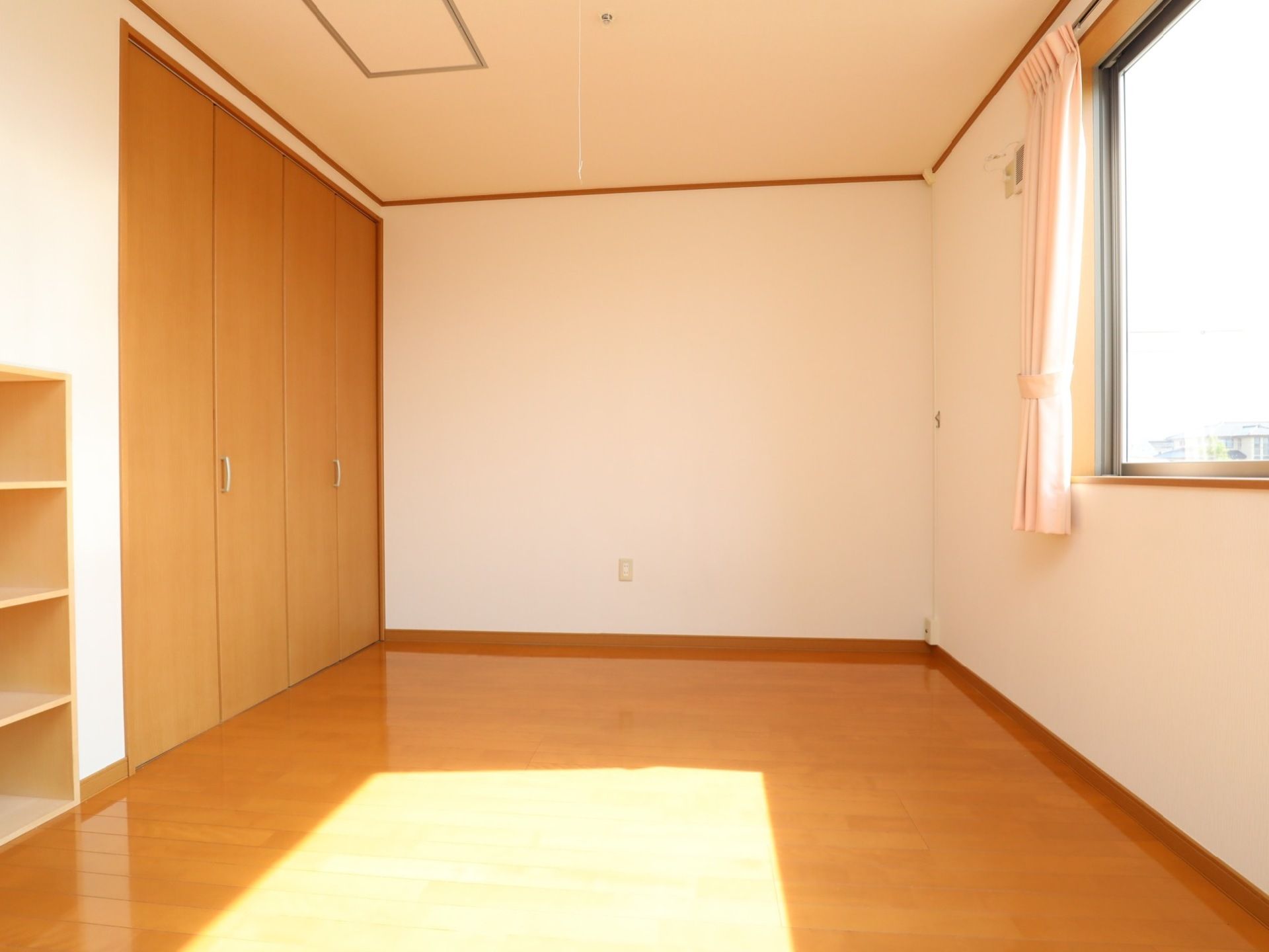 居室には、大きな窓から自然光が射し込み明るい空間である。横側に広々とした収納庫を備えている。壁にコンセントを設置している。