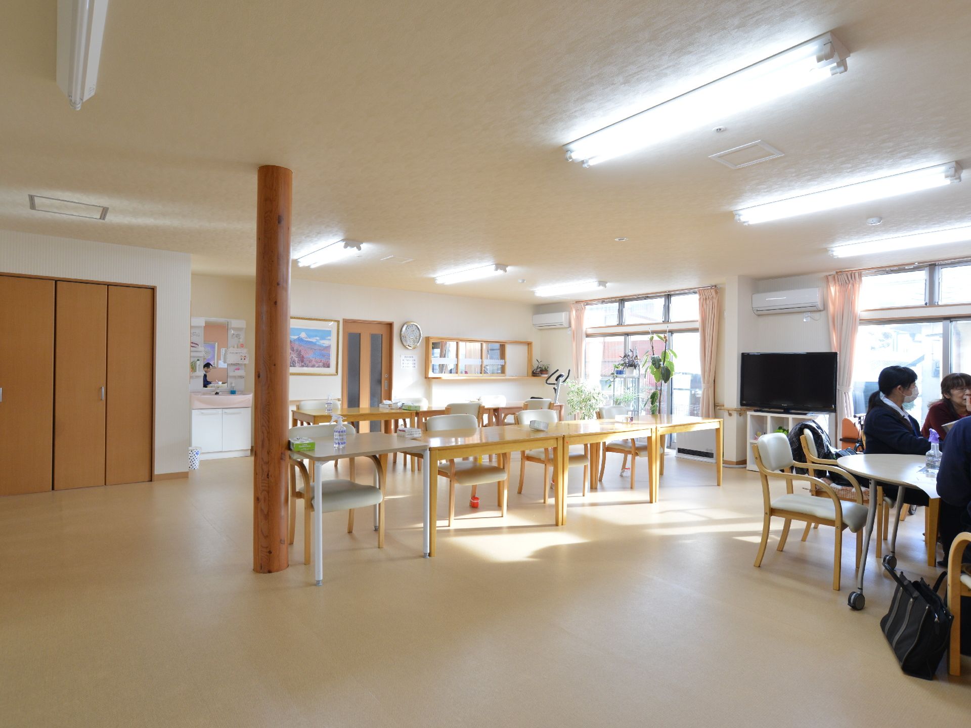 テーブル椅子などが設置してある多目的室。入居者とファミリーが面会ができる。トレーニングマシーン、テレビなどが設置。