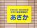 建物の茶色の外壁に貼られているプレート。板は黄色で、青字で施設名が書かれ、四隅をネジで固定されている。