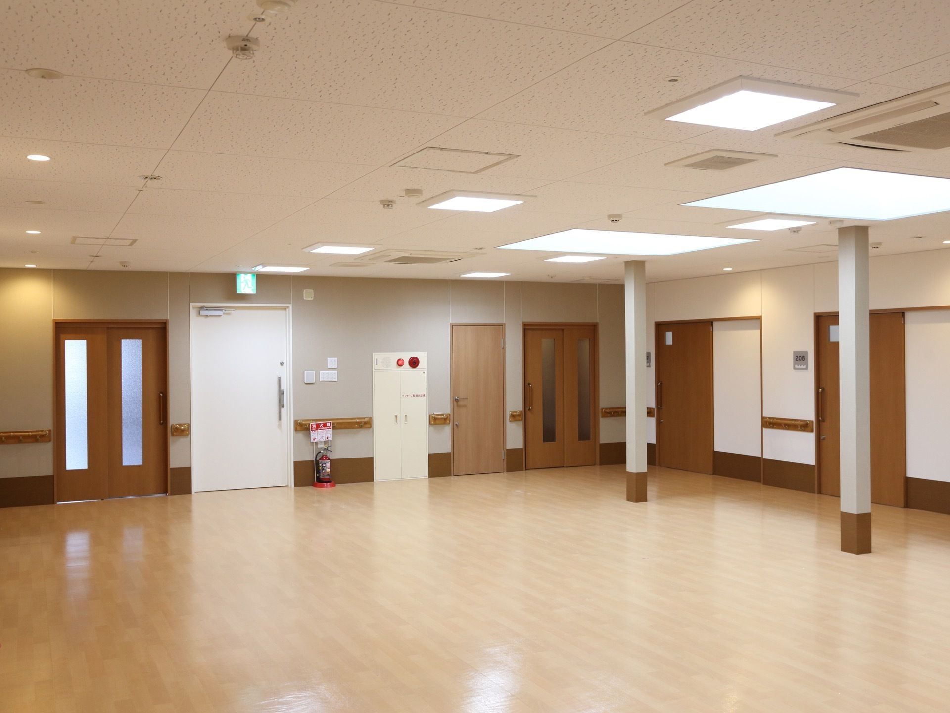 居室へのドアが二か所あり、その他にドアが三ヶ所ある。間柱が二本立っている。消火器と非常ベルが設置してある。