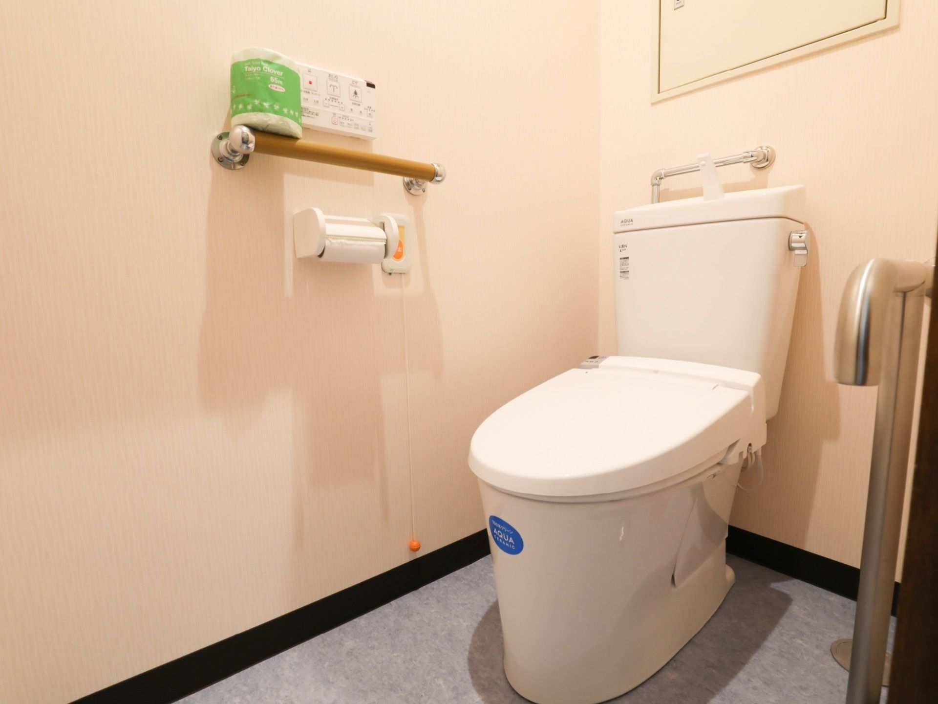 トイレには洋式便器が設置されている。ペーパーフォルダーの上には手すりがあり、そこには予備のトイレットペーパーが置かれている。