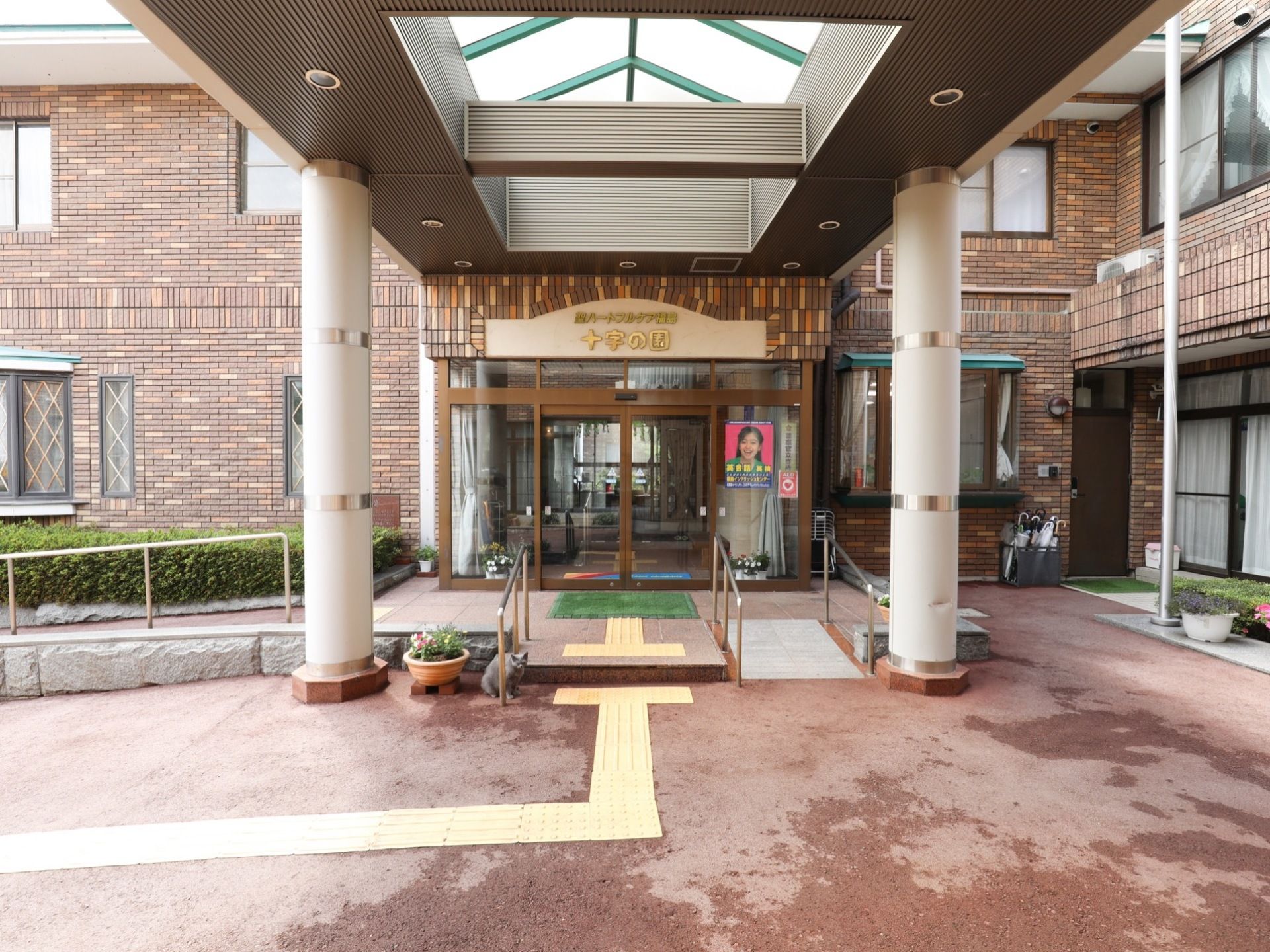 施設の入口はガラス扉があり、扉の前と横側には緩やかなスロープが設置されている。スロープには手すりがある。