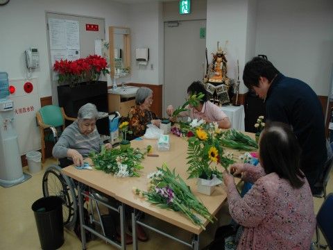 大きなテーブルを囲みながら、生け花を楽しむ入居者様たち