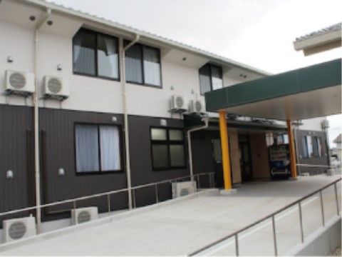 屋根のついた玄関で自動販売機が置かれている。建物の前には横幅のあるスロープが設置されており、両サイドには手すりが取り付けられている。