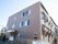 ３階建ての落ち着いた色合いの大きなグループホーム。入口前には手すりがついたスロープや階段が設置されている。