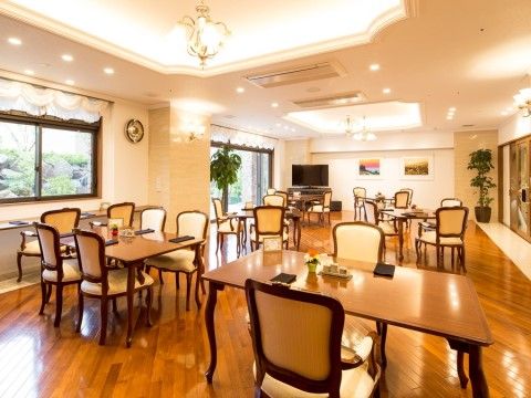 おしゃれな照明が、デザイン性のあるテーブルや椅子を照らす綺麗な食堂。窓の外には、手入れされた庭が見える。