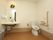 隅々まで清掃が行き届き、清潔に保たれているトイレである。左端には洗面台があり、鏡の上にリースが飾ってある。