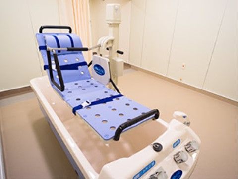 寝たままの姿勢で入浴できる介護浴槽。清潔感のある明るい部屋に置かれていて、部屋の入口にはプライバシーに配慮したカーテンが設置されている。