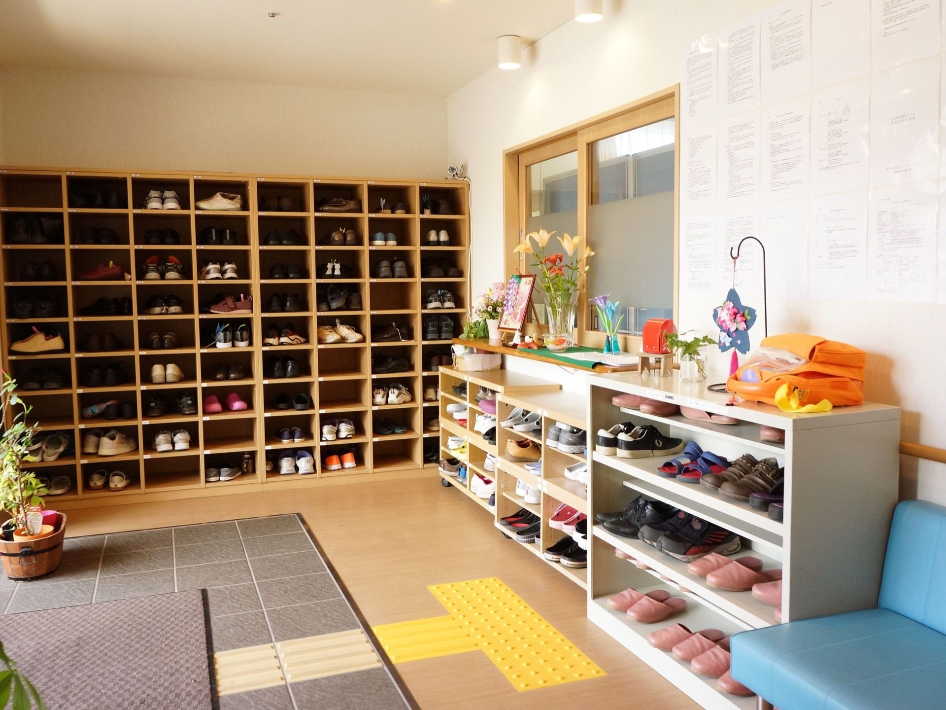 高さのある靴箱は個別に仕切られており、低い靴箱には靴やスリッパが入っている。床には点字ブロックが付いていて、入口にはマットが敷かれている。